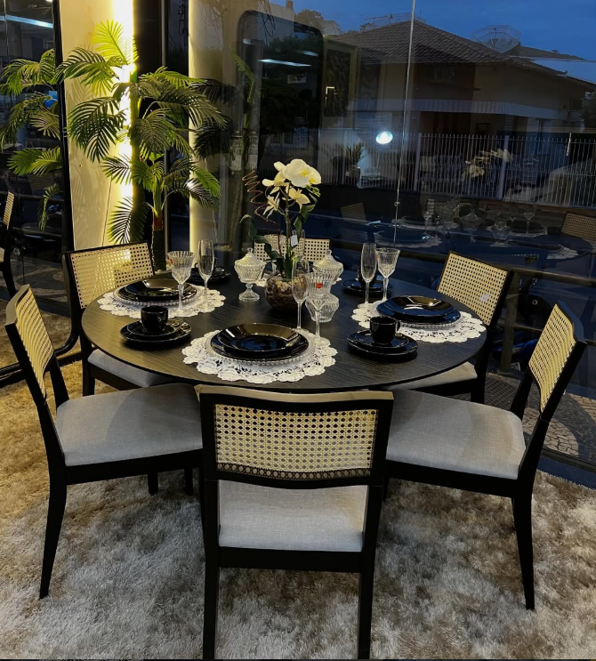 Mesa de jantar redonda com cadeiras de palhinha no showroom da JNF